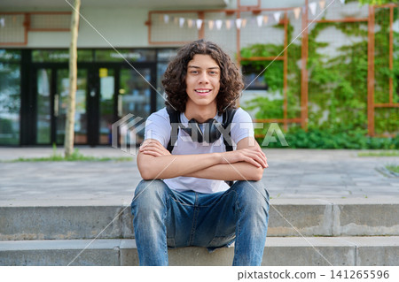 Happy young student with headphones sitting outside Happy young student with headphones sitting outside 141265596