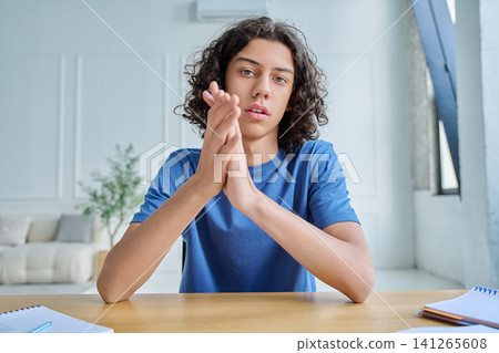 Serious teen boy listening during online lesson Serious teen boy listening during online lesson 141265608