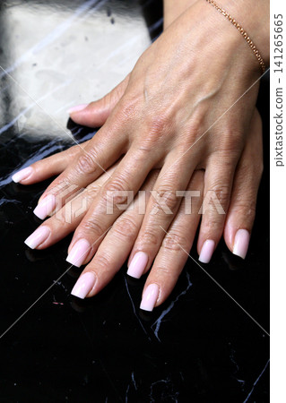 Receiving Professional Manicure in Modern Salon. Beautiful, well-groomed women's hands with elegant nails against a dark background. Beauty salon concept: manicures, pedicures. Receiving Professional Manicure in Modern Salon. Beautiful, well-groomed women's hands with elegant nails against a dark background. Beauty salon concept: manicures, pedicures. 141265665