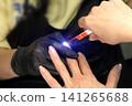 A woman's hand during a manicure. A woman getting a manicure. A manicurist is doing a client's nails at a nail salon. Manicure services. Nail art. Beauty salon. A woman's hand during a manicure. A woman getting a manicure. A manicurist is doing a client's nails at a nail salon. Manicure services. Nail art. Beauty salon. 141265688