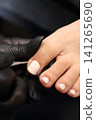 A woman's feet during a pedicure. Woman getting pedicure in beauty salon, closeup. Manicure services. Nail art. Pedicure, nail care, light-colored gel polish with rhinestones. Beauty salon concept: A woman's feet during a pedicure. Woman getting pedicure in beauty salon, closeup. Manicure services. Nail art. Pedicure, nail care, light-colored gel polish with rhinestones. Beauty salon concept: 141265690
