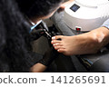 A woman's feet during a pedicure. Woman getting pedicure in beauty salon, closeup. A pedicurist working at a beauty salon. Manicure services. Nail art. Beauty salon concept: pedicures. A woman's feet during a pedicure. Woman getting pedicure in beauty salon, closeup. A pedicurist working at a beauty salon. Manicure services. Nail art. Beauty salon concept: pedicures. 141265691