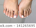 A woman's feet during a pedicure. Woman getting pedicure in beauty salon, closeup. Manicure services. Nail art. Pedicure, nail care, light-colored gel polish with rhinestones. Beauty salon concept: A woman's feet during a pedicure. Woman getting pedicure in beauty salon, closeup. Manicure services. Nail art. Pedicure, nail care, light-colored gel polish with rhinestones. Beauty salon concept: 141265695