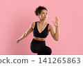 Focused young Black woman performing athletic running pose in activewear 141265863