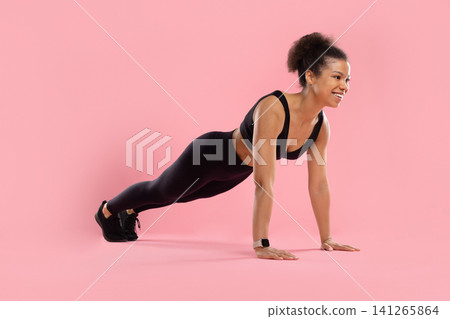 Cheerful young Black woman in sportswear holding high plank position Cheerful young Black woman in sportswear holding high plank position 141265864