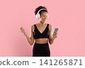 Smiling sporty African American woman with headphones checking smartphone 141265871