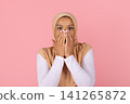 Surprised young Black Muslim woman in hijab covering mouth with both hands 141265872