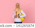 Black Muslim female student in hijab holding colorful notebooks and yellow backpack 141265874