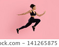 Young Black female athlete in activewear performing powerful split leap 141265875