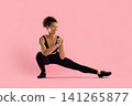 Cheerful young Black athlete in sportswear holding deep lateral lunge stretch 141265877