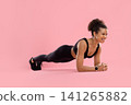 Smiling young Black female athlete in activewear performing forearm plank 141265882
