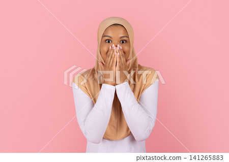 Surprised Black Muslim woman in beige hijab covering her mouth with hands Surprised Black Muslim woman in beige hijab covering her mouth with hands 141265883