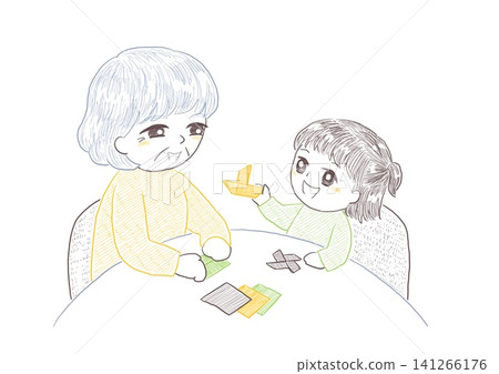 A senior woman enjoys playing with origami at a table with her grandchild. A senior woman enjoys playing with origami at a table with her grandchild. 141266176