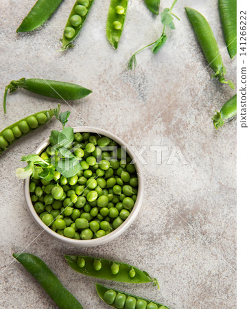 Fresh green peas in bowl and pods on rustic surface Fresh green peas in bowl and pods on rustic surface 141266222