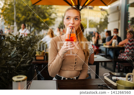 Young woman enjoying Aperol Spritz at outdoor cafe in Vienna Young woman enjoying Aperol Spritz at outdoor cafe in Vienna 141266560