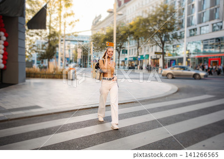 Young adult woman talking on phone crossing street in Vienna Young adult woman talking on phone crossing street in Vienna 141266565