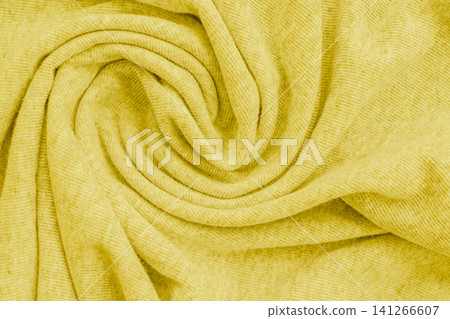 Horizontal macro close up of a soft bright yellow knitted fabric material texture twisted into a perfect spiral swirl pattern on a warm cozy sweater background 141266607