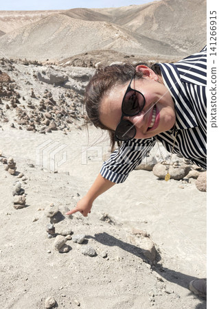Woman pointing at stone cairns in desert valley Woman pointing at stone cairns in desert valley 141266915