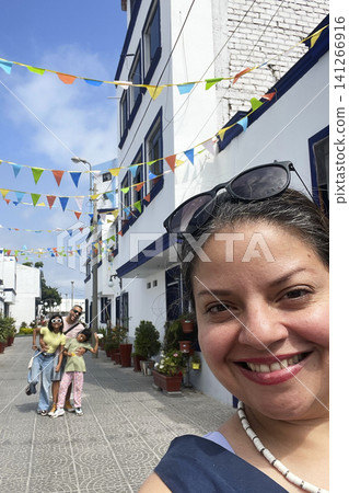 Family walking in picturesque street with colorful flags 141266916