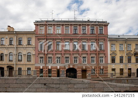 Beautiful buildings line the canal in St. Petersburg, displaying distinct architectural styles and colors under a partly cloudy sky, evoking history. Beautiful buildings line the canal in St. Petersburg, displaying distinct architectural styles and colors under a partly cloudy sky, evoking history. 141267155