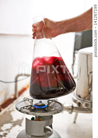 Hands, beaker and liquid at brewery for beer production with formula, gas burner and process. Person, worker and glass container for fluid on flame in industrial workshop for alcohol manufacturing Hands, beaker and liquid at brewery for beer production with formula, gas burner and process. Person, worker and glass container for fluid on flame in industrial workshop for alcohol manufacturing 141267199