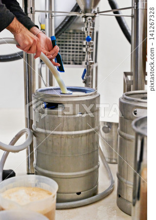 Brewery, tank and hands with pipe for craft beer in machine for production with manufacturing process, distillation or keg. Industrial industry, closeup or brewing in factory, warehouse or distillery Brewery, tank and hands with pipe for craft beer in machine for production with manufacturing process, distillation or keg. Industrial industry, closeup or brewing in factory, warehouse or distillery 141267328
