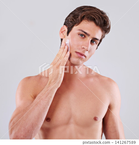 Handsome man, portrait and skincare with cream, grooming or hygiene on a gray studio background. Attractive male person or young model with lotion or moisturizer for facial treatment on mockup space Handsome man, portrait and skincare with cream, grooming or hygiene on a gray studio background. Attractive male person or young model with lotion or moisturizer for facial treatment on mockup space 141267589