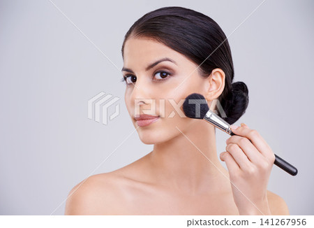 Woman, portrait and makeup application or brush in studio for beauty blush, cosmetics or grey background. Male person, face and treatment transformation for makeover wellness, mockup space or routine Woman, portrait and makeup application or brush in studio for beauty blush, cosmetics or grey background. Male person, face and treatment transformation for makeover wellness, mockup space or routine 141267956