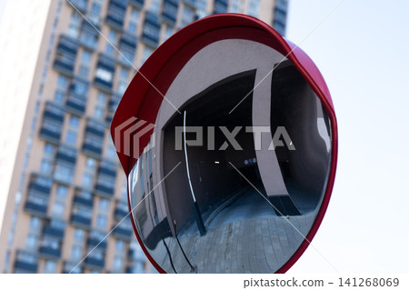 A Striking Urban Reflection: Red Convex Mirror Capturing the Distorted Facade of a Modern Building in a City Setting 141268069
