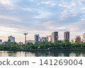 The city skyline and park trees reflected on the river surface at dusk. 141269004