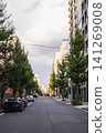 A city street lined with ginkgo trees and a cityscape of skyscrapers. 141269008