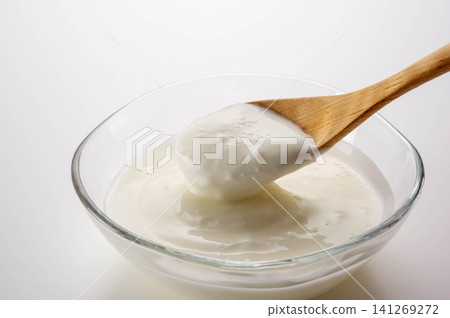 A scene of a table setting where yogurt is being scooped with a wooden spoon, a white dairy product. A scene of a table setting where yogurt is being scooped with a wooden spoon, a white dairy product. 141269272