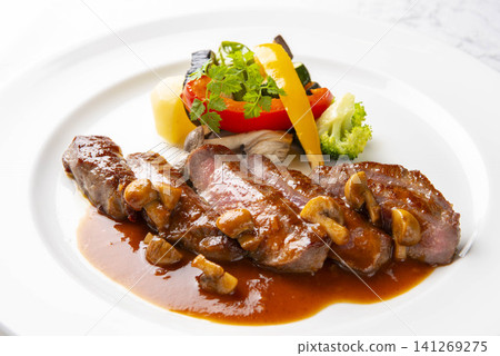 A fine French dish featuring a flavorful steak served with mushroom sauce and colorful vegetables. A fine French dish featuring a flavorful steak served with mushroom sauce and colorful vegetables. 141269275