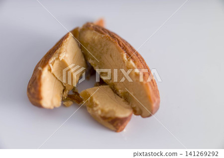 A close-up of a broken almond against a white background in a food photograph. A close-up of a broken almond against a white background in a food photograph. 141269292