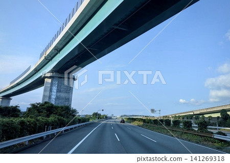 A view of a highway and elevated bridge running under a blue sky. A view of a highway and elevated bridge running under a blue sky. 141269318