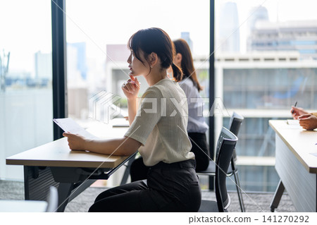 A woman reading documents while looking out the window. A woman reading documents while looking out the window. 141270292