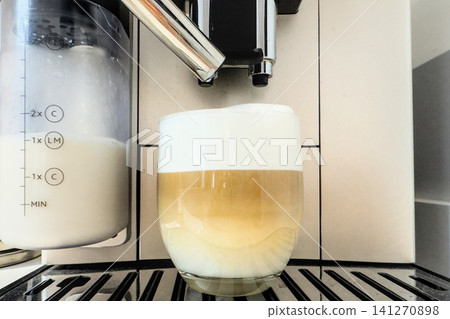 A finished latte macchiato with distinct coffee and milk layers and foam on top in a clear glass. Ready layered drink A finished latte macchiato with distinct coffee and milk layers and foam on top in a clear glass. Ready layered drink 141270898