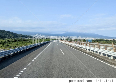 A road view overlooking a highway and city under a blue sky. 141271841