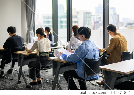 Multiple business people reading documents in a conference room. Multiple business people reading documents in a conference room. 141271865