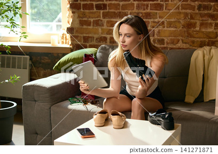 Woman checking black loafer against online fashion catalog on tablet. Woman checking black loafer against online fashion catalog on tablet. 141271871
