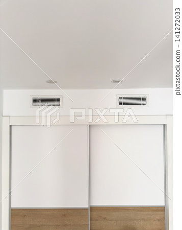 Two linear ceiling diffusers of a ducted air conditioner above a wardrobe. Concealed ventilation and air distribution 141272033