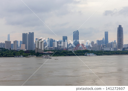 Wuhan city skyline along a wide river featuring a red arch bridge Wuhan city skyline along a wide river featuring a red arch bridge 141272607