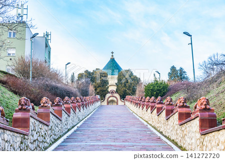 A path lined with reddish-brown ceramic lion statues leads to the Zsolnay Mausoleum in the World Heritage city of Pécs. A path lined with reddish-brown ceramic lion statues leads to the Zsolnay Mausoleum in the World Heritage city of Pécs. 141272720