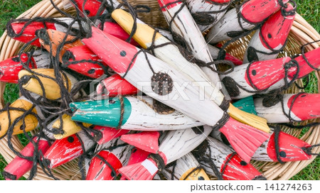 Top view of handcrafted colorful wooden fish decorations in a wicker basket. Top view of handcrafted colorful wooden fish decorations in a wicker basket. 141274263
