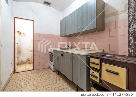 Abandoned kitchen showing old appliances and worn pink tiles Abandoned kitchen showing old appliances and worn pink tiles 141274590