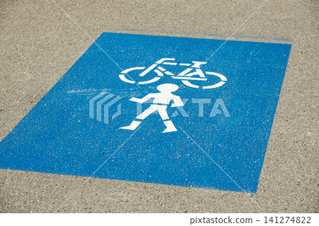 Blue road marking indicating a shared pedestrian and bicycle lane on the asphalt Blue road marking indicating a shared pedestrian and bicycle lane on the asphalt 141274822