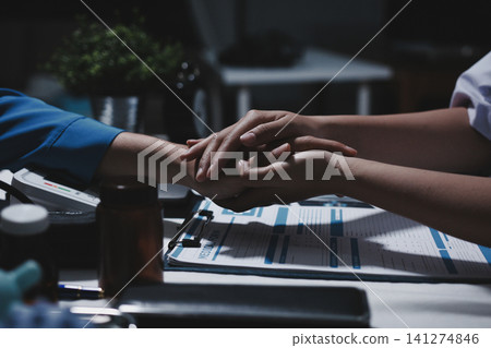 Professional Doctor Offers Comforting Support Holding a Patients Hand During Medical Consultation Professional Doctor Offers Comforting Support Holding a Patients Hand During Medical Consultation 141274846
