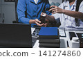 Two asian women doctors discuss meeting doctor's office medical clinic looking x-ray film consulting patient disease. Asian medical lab young women talking together discussing healthcare teamwork 141274860