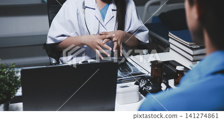 Two asian women doctors discuss meeting doctor's office medical clinic looking x-ray film consulting patient disease. Asian medical lab young women talking together discussing healthcare teamwork Two asian women doctors discuss meeting doctor's office medical clinic looking x-ray film consulting patient disease. Asian medical lab young women talking together discussing healthcare teamwork 141274861