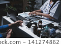Two asian women doctors discuss meeting doctor's office medical clinic looking x-ray film consulting patient disease. Asian medical lab young women talking together discussing healthcare teamwork 141274862